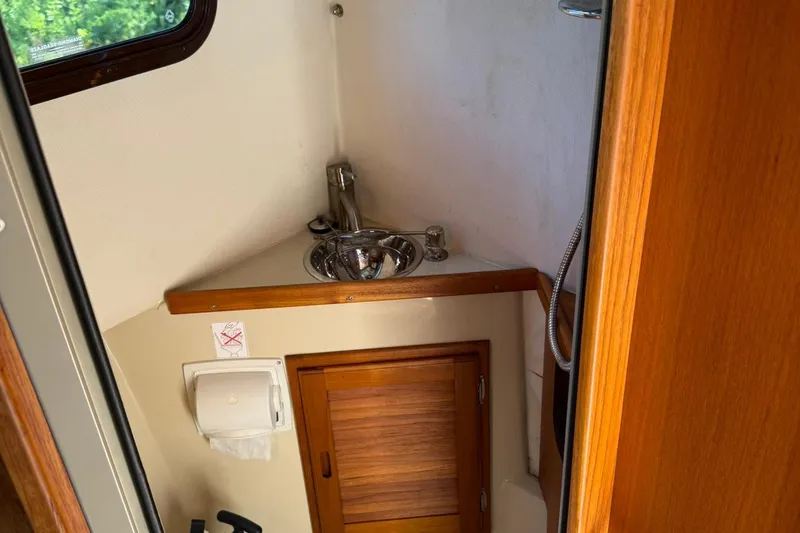 Slide: The Image of 2010 Ranger Tugs R-25 boat bathroom with sink, wooden cabinet, and window. - 40