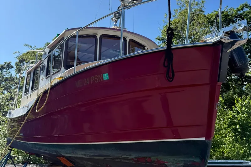 Slide: The Image of 2010 Ranger Tugs R-25 boat with red hull, docked outdoors under clear blue sky. - 6