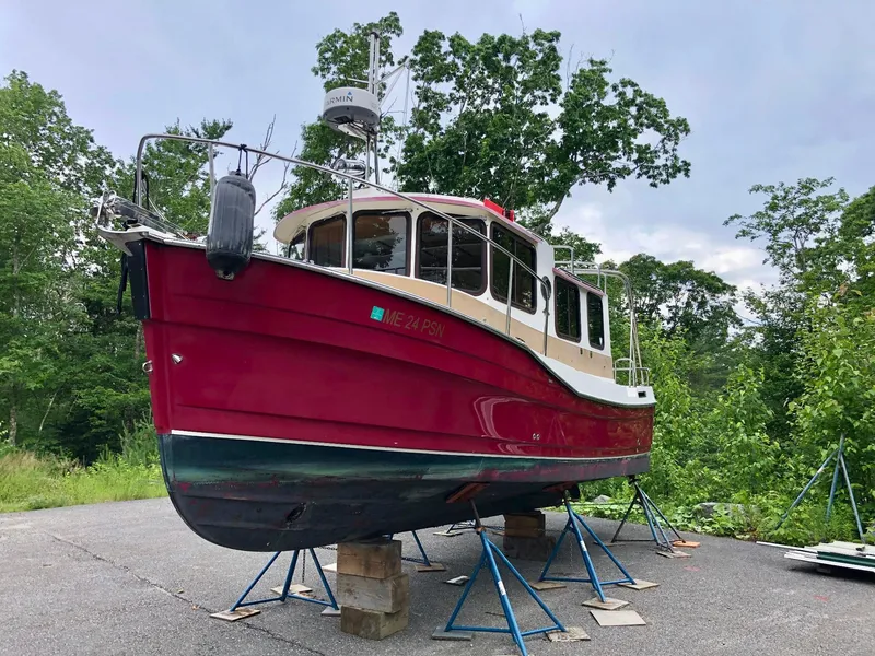 Slide: The Image of 2010 Ranger Tugs R-25 boat on stands, red hull, surrounded by trees. - 8