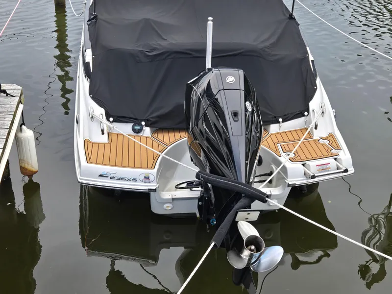 Slide: The Image of 2022 Crownline Eclipse E235 XS boat docked with covered deck and outboard motor. - 10