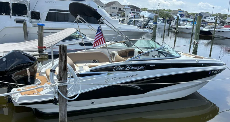 Slide: The Image of 2022 Crownline Eclipse E235 XS boat docked in marina, featuring sleek design and American flag. - 17