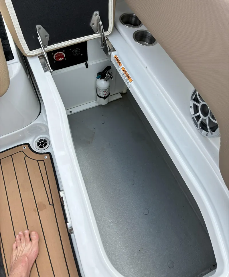 Slide: The Image of 2022 Crownline Eclipse E235 XS boat storage compartment with cup holders and fire extinguisher. - 18