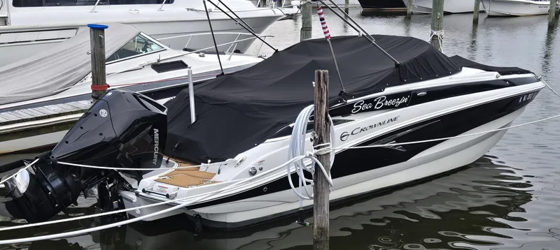 Slide: The Image of 2022 Crownline Eclipse E235 XS boat docked with cover, featuring Mercury outboard engine. - 2