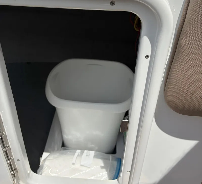 Slide: The Image of Storage compartment in 2022 Crownline Eclipse E235 XS boat with a white bin inside. - 23