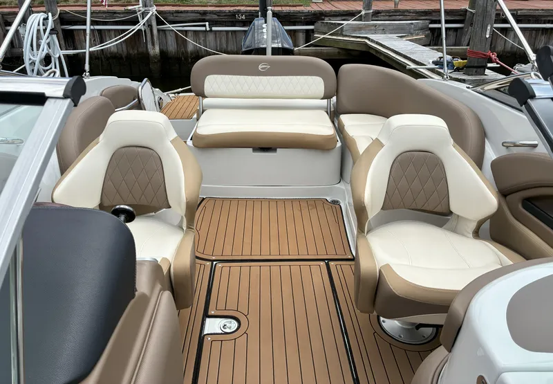 Slide: The Image of 2022 Crownline Eclipse E235 XS boat interior with tan and white seating, wood-style flooring. - 3