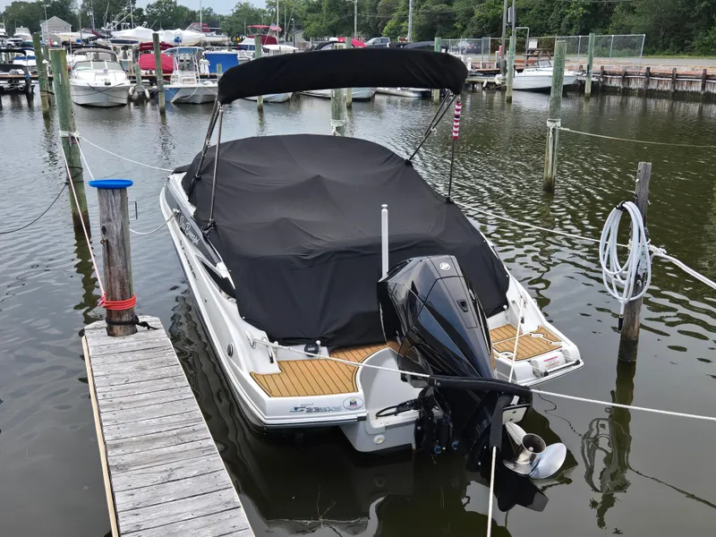 Slide: The Image of 2022 Crownline Eclipse E235 XS boat docked with cover on, in a marina setting. - 9