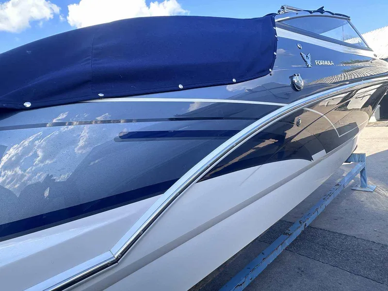 Slide: The Image of 2016 Formula 240 Bowrider boat with blue cover, sleek design, and reflective finish. - 3