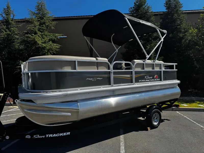 The Image of 2025 Sun Tracker Party Barge 18 DLX pontoon boat on trailer, parked outdoors. - 0