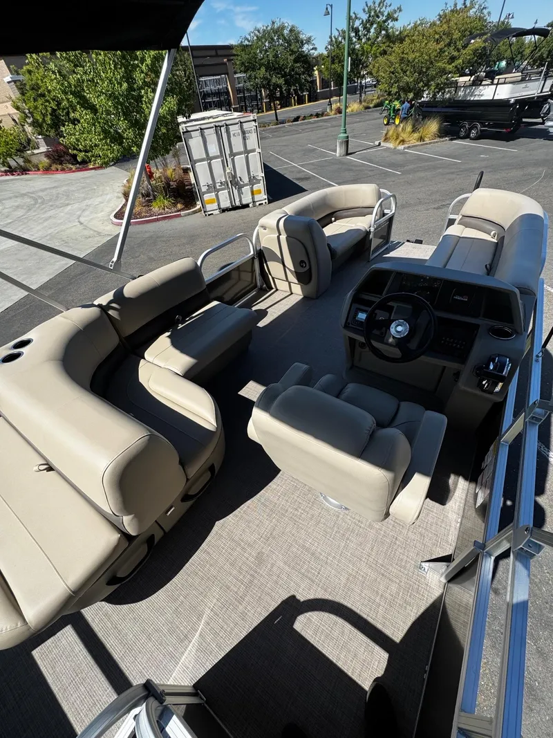 Slide: The Image of 2025 Sun Tracker Party Barge 18 DLX interior with beige seating and steering console. - 7