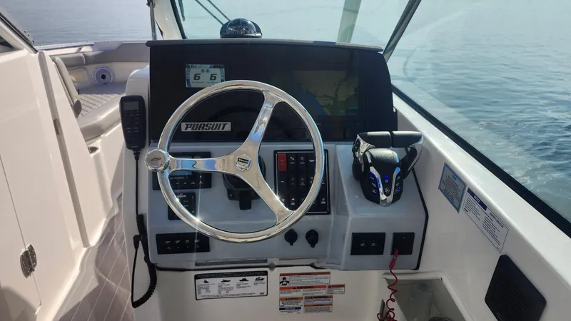 Slide: The Image of 2024 Pursuit DC 266 Dual Console boat dashboard with steering wheel and controls. - 1