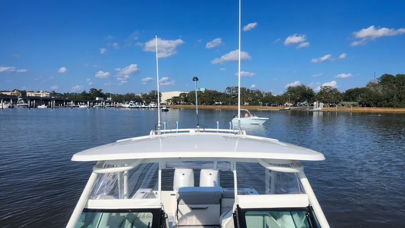Slide: The Image of 2024 Pursuit DC 266 Dual Console boat on calm water under a clear blue sky. - 12