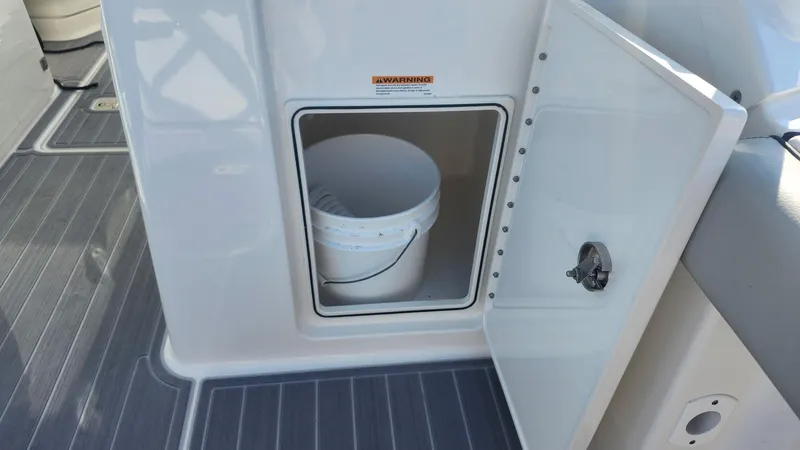 Slide: The Image of 2024 Pursuit DC 266 Dual Console storage compartment with bucket on deck. - 16