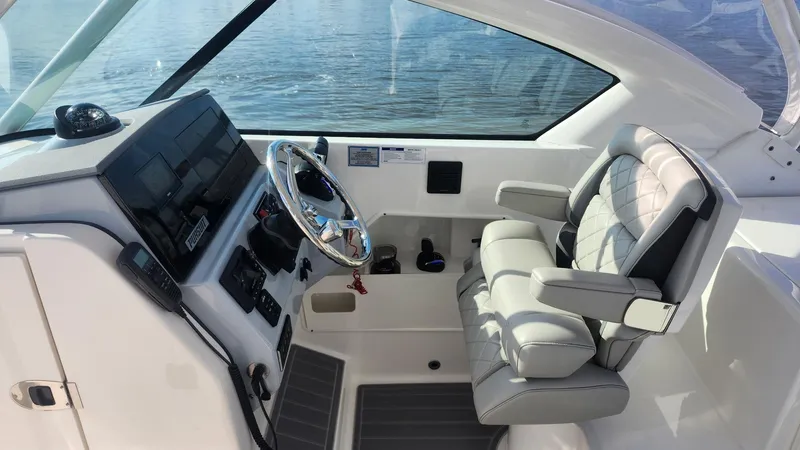 Slide: The Image of 2024 Pursuit DC 266 Dual Console boat interior with steering wheel and cushioned seat. - 2