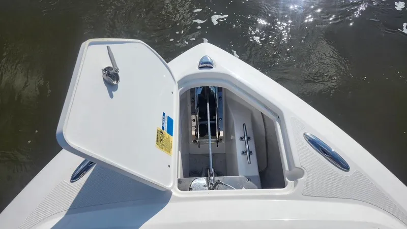 Slide: The Image of 2024 Pursuit DC 266 Dual Console anchor locker open on calm water. - 22