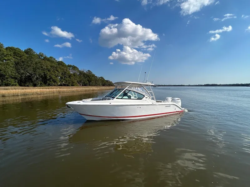 Slide: The Image of 2024 Pursuit DC 266 Dual Console boat on calm water under blue sky. - 25