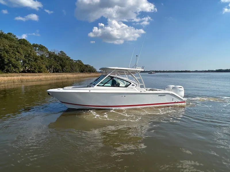 Slide: The Image of 2024 Pursuit DC 266 Dual Console boat cruising on a calm river under a clear blue sky. - 28