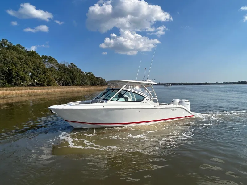 Slide: The Image of 2024 Pursuit DC 266 Dual Console boat cruising on a calm lake under a clear blue sky. - 29