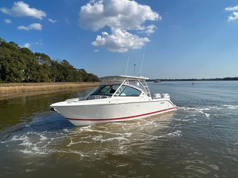 Slide: The Image of 2024 Pursuit DC 266 Dual Console boat cruising on a calm lake under a clear blue sky. - 30