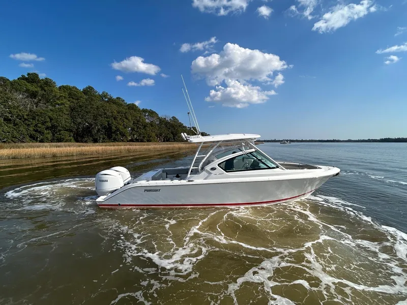 Slide: The Image of 2024 Pursuit DC 266 Dual Console boat cruising on a calm lake under a clear blue sky. - 35