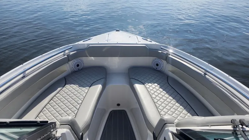 Slide: The Image of 2024 Pursuit DC 266 Dual Console boat interior with cushioned seating on calm water. - 9
