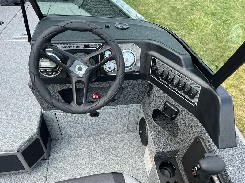 Slide: The Image of 2026 Lund 1875 Impact XS Sport boat dashboard with steering wheel and control panel. - 16