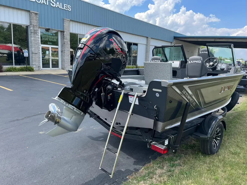 Slide: The Image of 2026 Lund 1875 Impact XS Sport boat displayed outside dealership, featuring powerful outboard motor. - 3