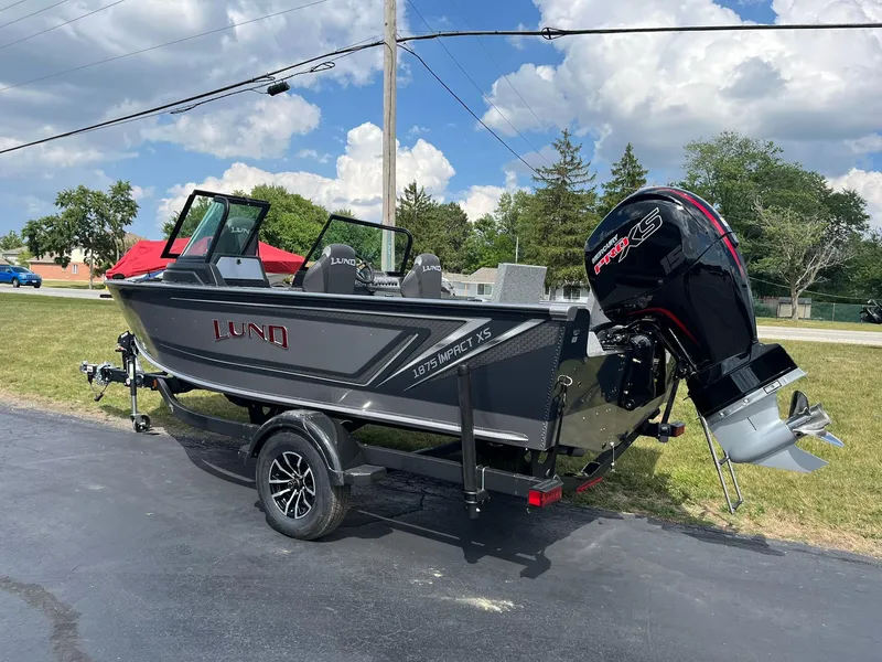 Slide: The Image of 2026 Lund 1875 Impact XS Sport boat on trailer, parked outdoors under a cloudy sky. - 4