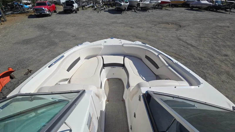 Slide: The Image of 2018 Chaparral 224 Sunesta boat with spacious seating, parked in a boatyard. - 16