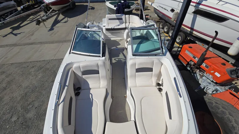 Slide: The Image of 2018 Chaparral 224 Sunesta boat interior with white seating, docked near other boats. - 20