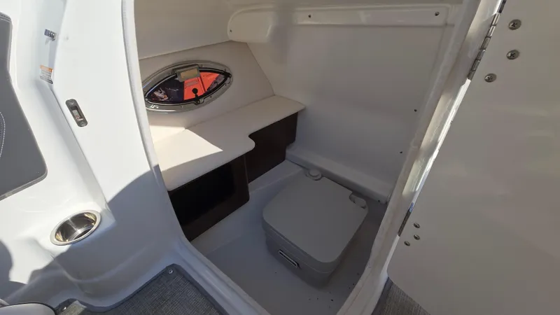 Slide: The Image of 2018 Chaparral 224 Sunesta boat interior with compact restroom and porthole window. - 40