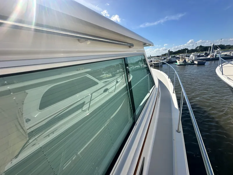 Slide: The Image of 2014 Back Cove 37 yacht docked, reflecting sunlight on calm water. - 12