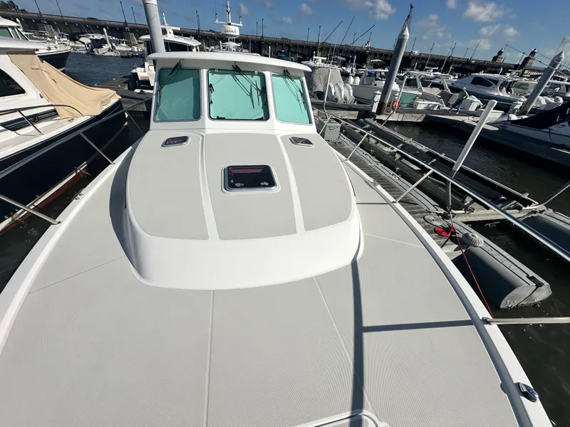 Slide: The Image of 2014 Back Cove 37 boat docked at marina, showcasing sleek deck design and clear skies. - 19