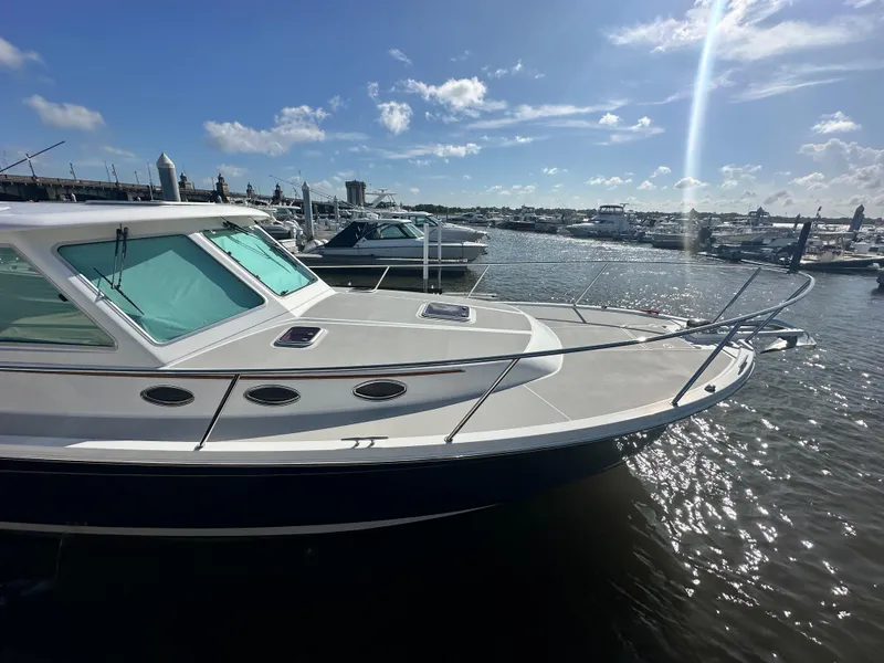 Slide: The Image of 2014 Back Cove 37 boat docked in a sunny marina, surrounded by other vessels. - 2