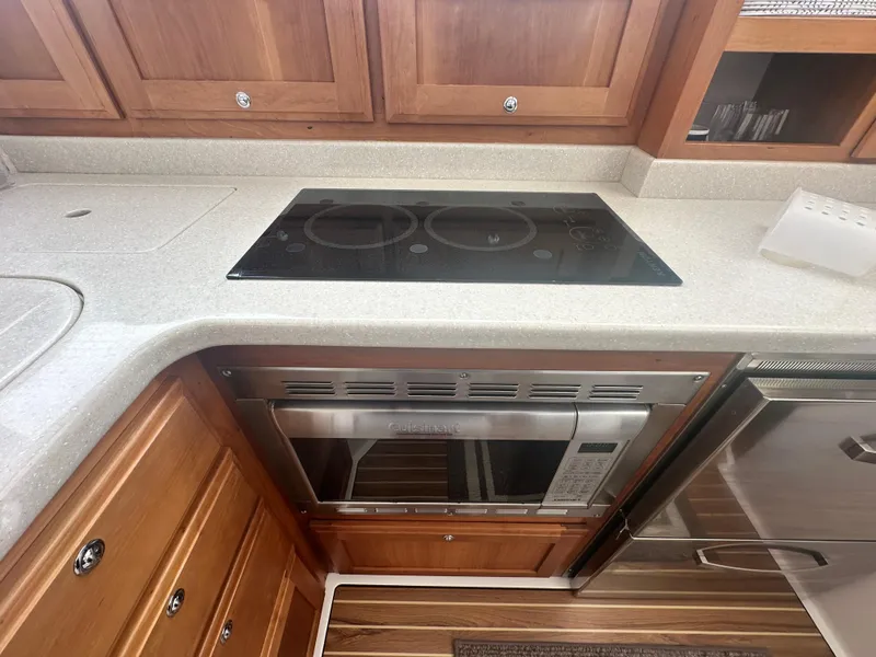 Slide: The Image of 2014 Back Cove 37 yacht kitchen with stove, microwave, and wooden cabinetry. - 40