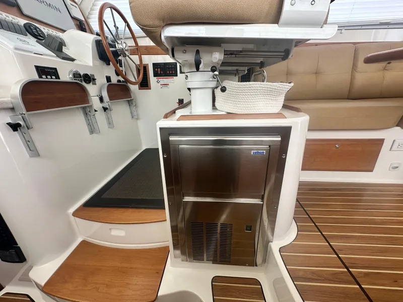 Slide: The Image of Interior of 2014 Back Cove 37 boat with helm, wooden steps, and stainless steel fridge. - 44