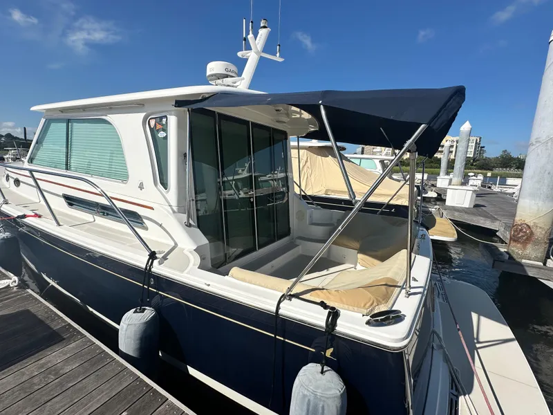 Slide: The Image of 2014 Back Cove 37 yacht docked, featuring a blue canopy and sleek design. - 6