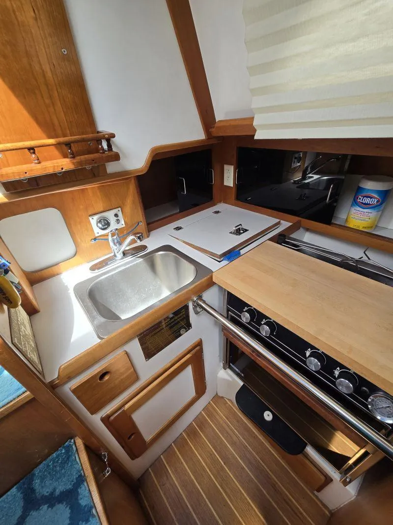 Slide: The Image of Compact kitchen in a 1993 Freedom Cruising sloop with sink, stove, and wooden cabinetry. - 16