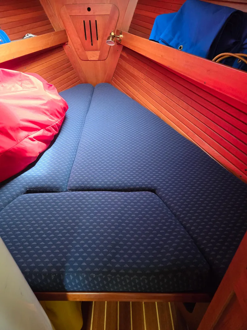 Slide: The Image of Cozy cabin interior of 1993 Freedom Cruising sloop with blue cushions and wooden paneling. - 26
