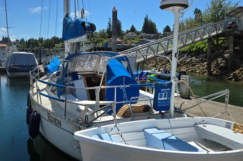 Slide: The Image of 1993 Freedom Cruising Sloop docked at marina with blue covers and nearby dinghy. - 3