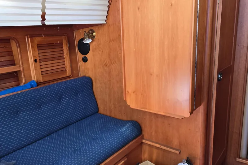 Slide: The Image of Interior of 1993 Freedom Cruising Sloop with blue cushioned seating and wooden cabinetry. - 33
