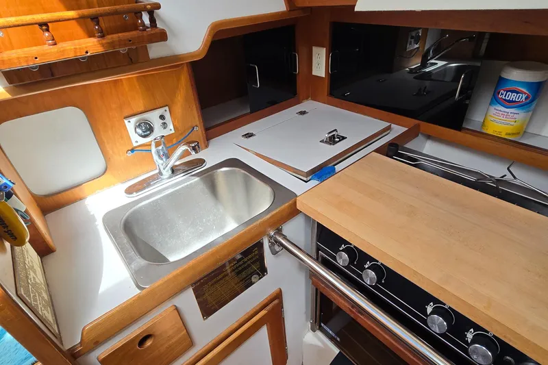 Slide: The Image of Compact kitchen area in a 1993 Freedom Cruising sloop with sink, stove, and wooden countertops. - 41
