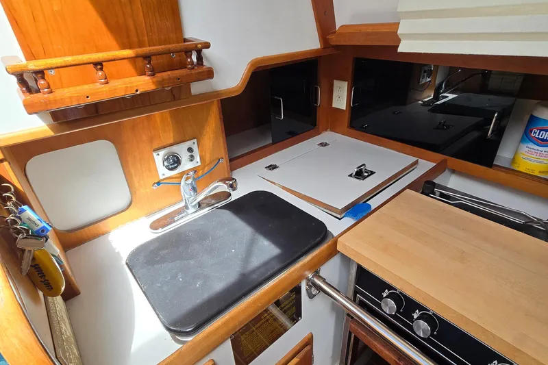 Slide: The Image of Compact kitchen area in a 1993 Freedom Cruising sloop with sink, stove, and wooden accents. - 42