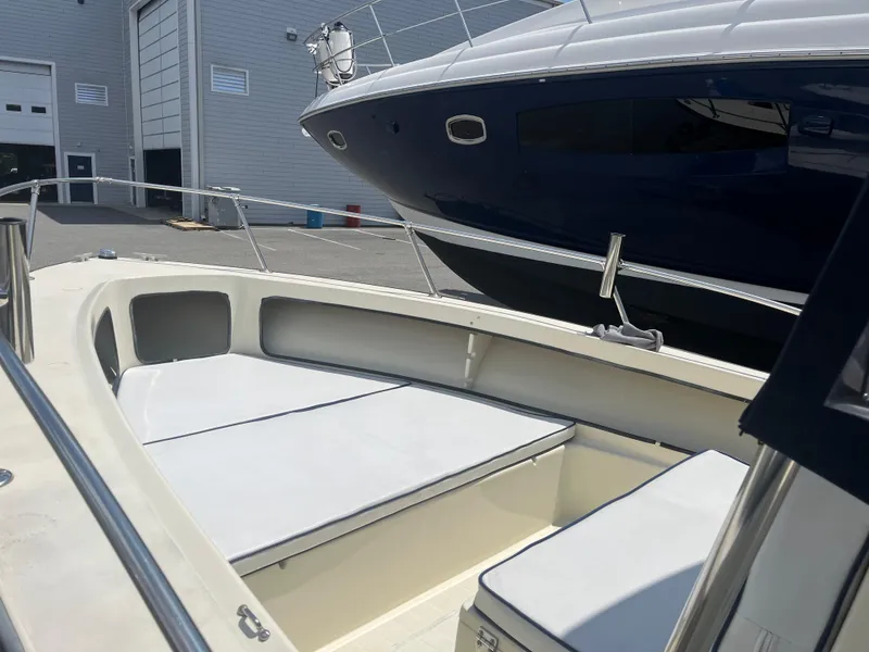 Slide: The Image of 1975 SeaCraft 20 Classic boat interior with white seating, docked near a larger vessel. - 11