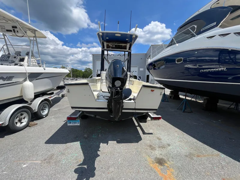 Slide: The Image of 1975 SeaCraft 20 Classic boat with outboard motor, parked between other boats under a blue sky. - 3