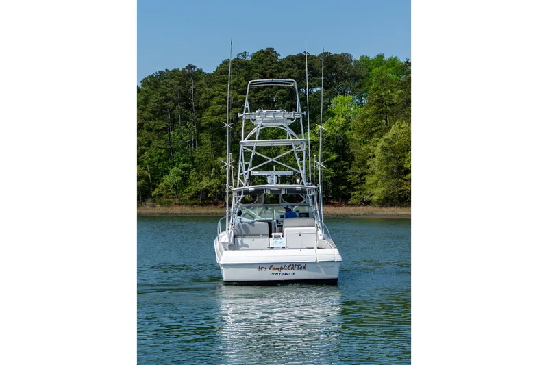 Slide: The Image of 2004 Stamas 370 Express boat on a serene lake with lush green forest backdrop. - 19