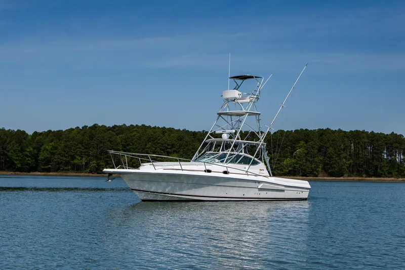 Slide: The Image of 2004 Stamas 370 Express boat on calm water with forested shoreline background. - 20