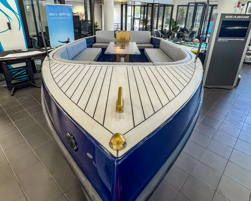 Slide: The Image of 2025 Vision Marine Technologies Volt 180 boat displayed indoors, featuring sleek seating and modern design. - 2