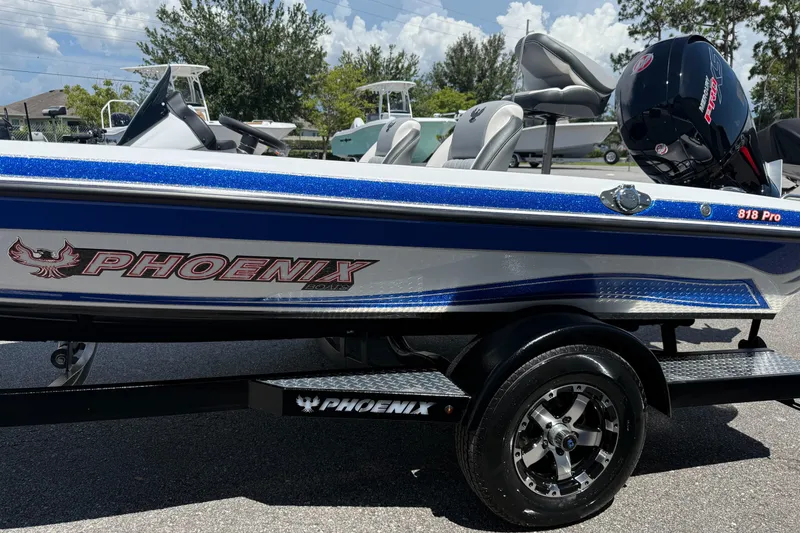 Slide: The Image of 2026 Phoenix ZXL 818 PRO boat with blue accents on a trailer, parked outdoors. - 14