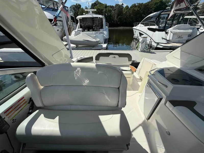 Slide: The Image of 2013 Monterey 280 SCR boat interior with white seating and docked yachts in background. - 4