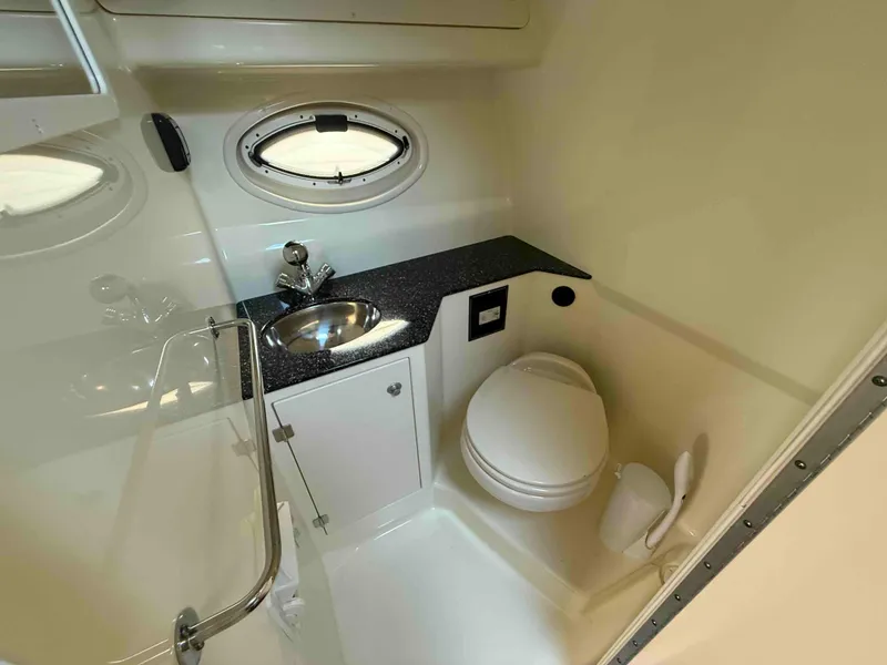 Slide: The Image of 2013 Monterey 280 SCR boat bathroom with sink, toilet, and porthole window. - 8